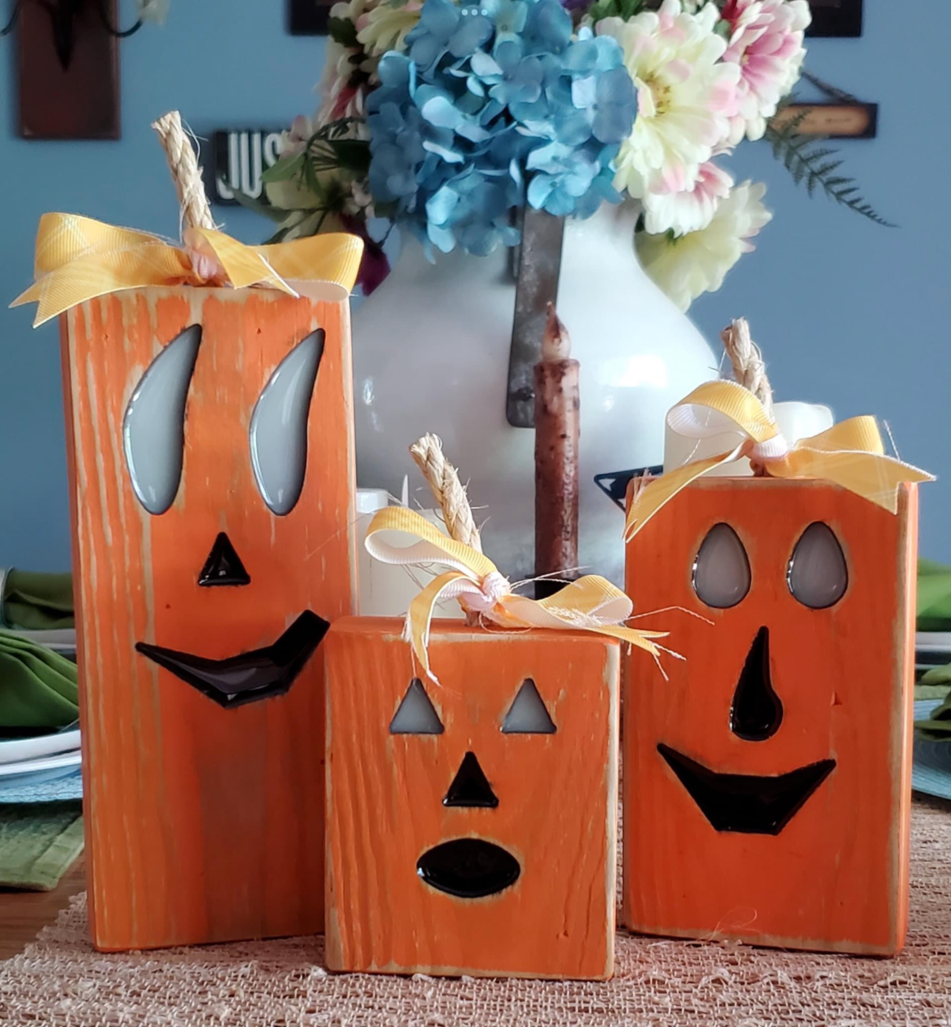 3 painted wooden pumpkins with glow in the dark resin eyes and a ribbon